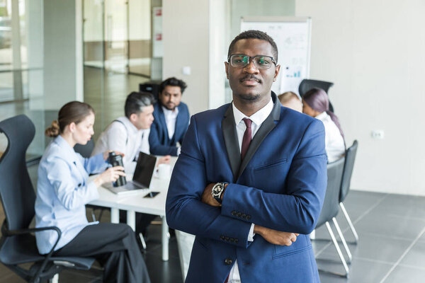 Business man stands on the background of partners. A team of young businessmen working and communicating together in an office. Corporate businessteam and manager in a meeting.