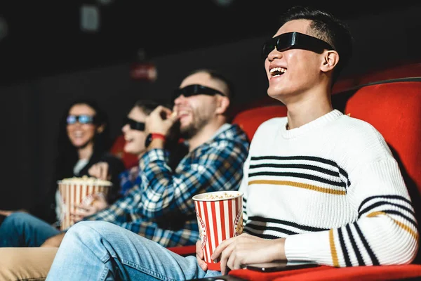 Amigos viendo una película en el cine con palomitas de maíz. La gente se sienta en los sillones del cine y mira la pantalla con gafas especiales para 3D — Foto de Stock