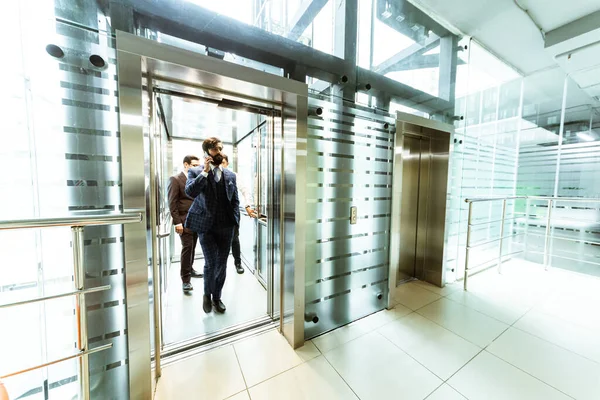 Grupo de negocios en ascensor. Gente de negocios en un gran ascensor de cristal en una oficina moderna. Corporativossteam y gerente en una reunión. — Foto de Stock
