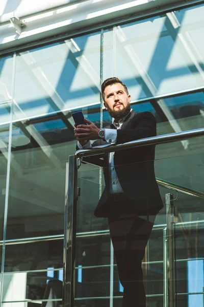 Retrato de un hombre de negocios en traje están de pie en el fondo de las oficinas de vidrio. — Foto de Stock