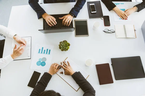 Grupo de jóvenes empresarios que trabajan y se comunican sentados en el escritorio de la oficina junto con sus colegas sentados. reunión de negocios. Escritorio vista superior. — Foto de Stock