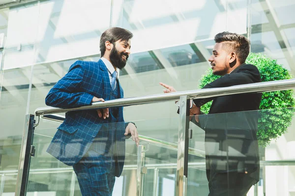 Jóvenes empresarios están de pie y hablando en el fondo de las oficinas de vidrio. Corporativossteam y gerente en una reunión. — Foto de Stock