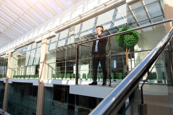 Retrato de un hombre de negocios en traje están de pie en el fondo de las oficinas de vidrio. — Foto de Stock