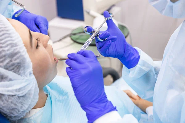 Dentistry concept. Professional dental services and modern equipment without pain. A doctor with an assistant treats the patients teeth and gives an anesthetic injection