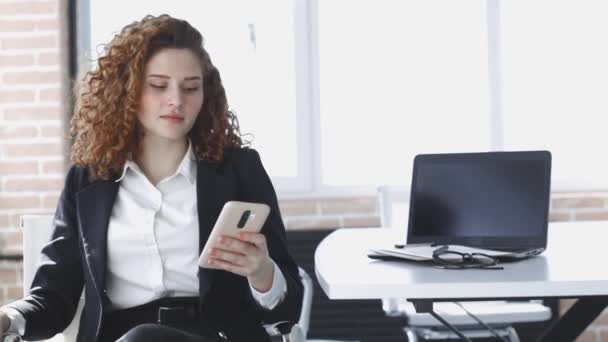 Sonriendo joven mujer de negocios profesional hablando por teléfono usando el ordenador portátil sentarse en la oficina — Vídeo de stock