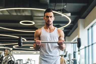 Spor salonunda halter egzersizi yapan yakışıklı genç sporcu.