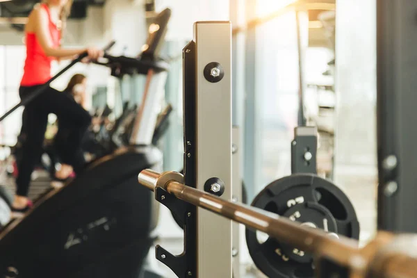 Parte de un banco de atletismo con una barra en un fondo borroso de un gimnasio grande y personas haciendo ejercicios — Foto de Stock