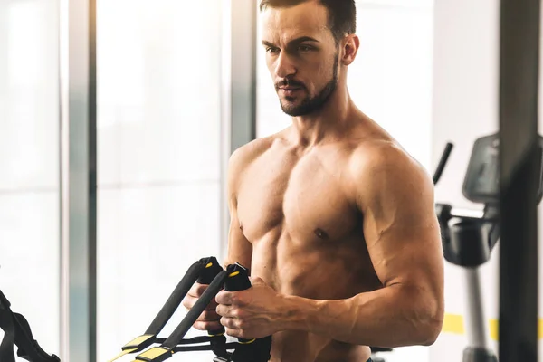 Beau jeune bodybuilder masculin sportif avec torse nu faisant des exercices dans la salle de gym — Photo