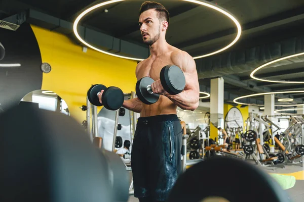 Jóképű fiatal sportos férfi testépítő csinál súlyzó gyakorlat tornaterem — Stock Fotó
