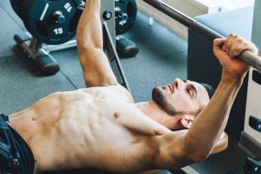 Atletik adam halter egzersizi yapıyor. Profesyonel vücut geliştirici halterle ağırlık çalışması yapıyor.