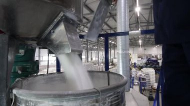 Bir işçi, otomatikman karıştırıcıdan çıkan hammaddeleri fabrikadaki varillere ve poşetlere doldurur. Polipropilen ürünlerinin üretimi