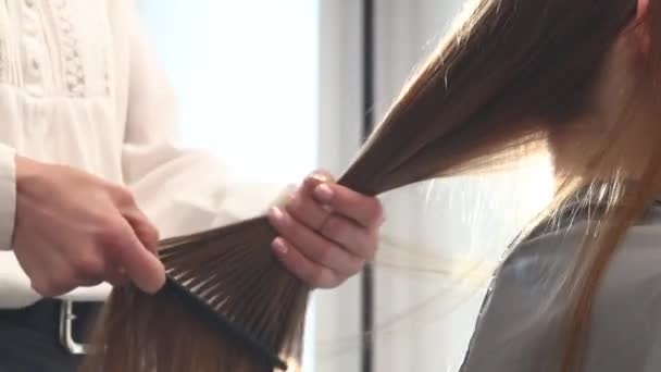 Close-up fryzjer grzebie włosy dziewcząt poprzez stylizację w salonie piękności. — Wideo stockowe
