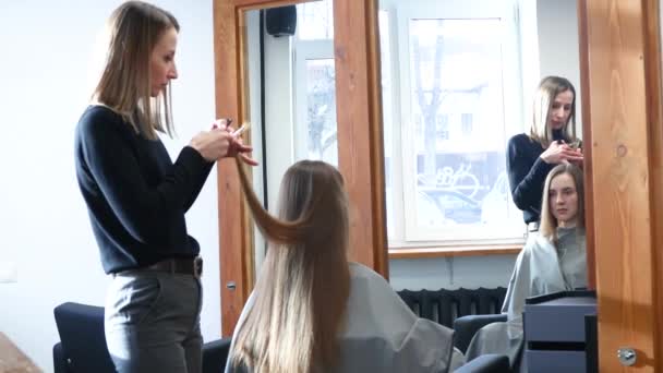 El peluquero maestro corta las puntas del pelo de las niñas después de lavarse en el salón de belleza de cerca — Vídeos de Stock