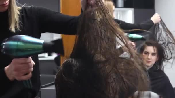 Maestra mujer peluquería seca el pelo de las niñas con un secador de pelo después de lavarse en un salón de belleza. — Vídeos de Stock