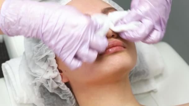 Cuidados faciais e proteção da pele. Uma jovem mulher num encontro de esteticistas. O especialista limpa a pele antes de aplicar o creme de máscara — Vídeo de Stock