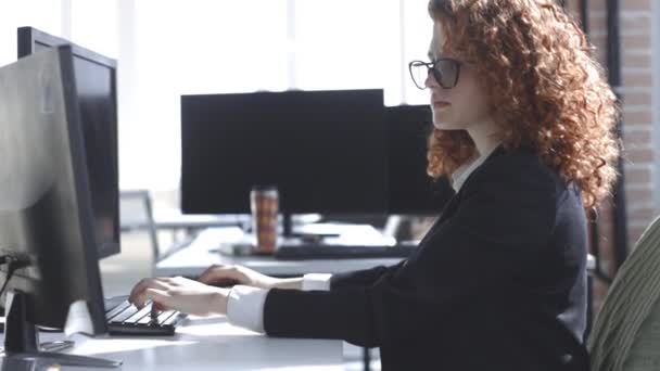 Genç kadın ofisteki bilgisayarın başında çalışıyor. Çalışan iş kadını — Stok video