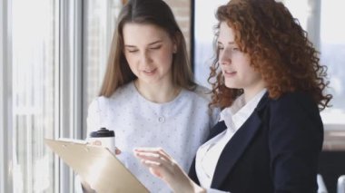 Ofiste birlikte çalışan iki genç kadın. Takım çalışması, iş toplantısı. Bağımsızlar çalışır.