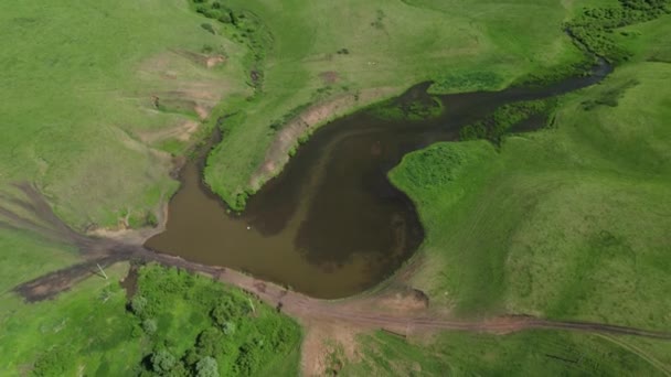 4k Luftaufnahme eines kleinen Sees inmitten landwirtschaftlicher Felder und grüner Wiesen in der Landschaft. Drohnenschießen — Stockvideo