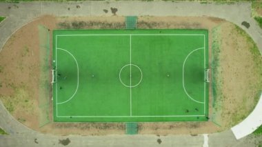 Futbol sahasının yukarıdan görünüşü. Çocuklar taşra bir kasabada futbol oynarlar. Hava aracı 4K görüntüsü