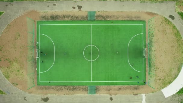 Vista de arriba hacia abajo del campo de fútbol. Los niños juegan al fútbol en una ciudad provincial. Imágenes aéreas de drones 4K — Vídeo de stock