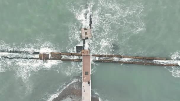 Légi felvétel egy drónról. A part mentén repül. Unalmas árapály. A hullámok ütköznek a hullámtörőkkel. — Stock videók