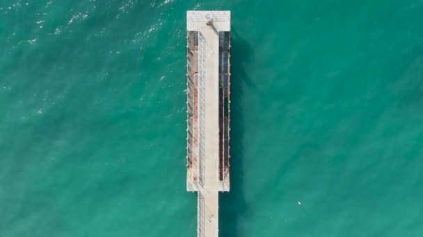 Luftaufnahme der alten Seebrücke, die von der azurblauen Brandung angespült wurde. Von oben bis unten von der Drohne — Stockvideo