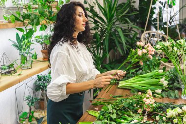 Çekici genç bayan çiçekçi bir çiçekçide çalışıyor..