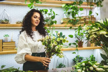 Çekici genç bayan çiçekçi bir çiçekçide çalışıyor..