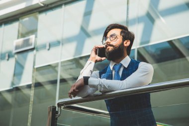 Cam ofislerin arka planında takım elbiseli bir işadamının portresi duruyor..