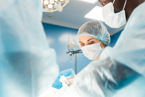 Een internationaal team van artsen voert een complexe chirurgische ingreep uit op een patiënt onder narcose. Moderne operatiekamer en ervaren chirurgen redden levens — Stockfoto