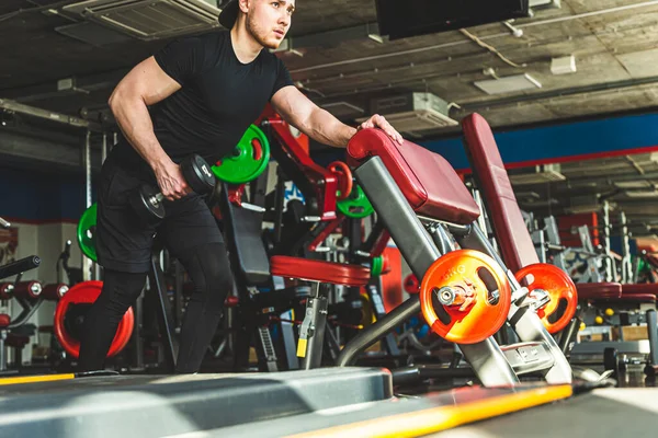 Jeune athlète masculin effectue des exercices dans la salle de gym avec haltères. Entraînement de force d'endurance — Photo