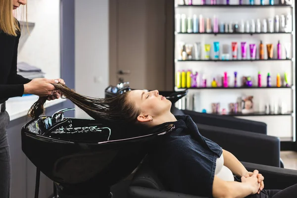 Friseurmeisterin wäscht die Haare der Mädchen sanft mit Shampoo und Conditioner, bevor sie sich in einem Schönheitssalon stylt. — Stockfoto