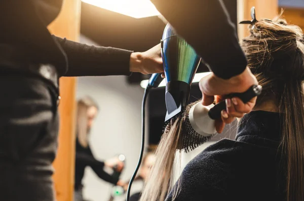 Maître femme coiffeur sèche les cheveux des filles avec un sèche-cheveux après le lavage dans un salon de beauté. — Photo