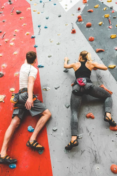 Двое спортсменов поднимаются по крутой скале, взбираются на искусственную стену в помещении. Экстремальные виды спорта и боулдеринг — стоковое фото