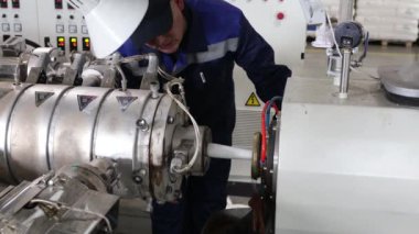 Bir işçi bir fabrikada teknolojik ekipman kuruyor..
