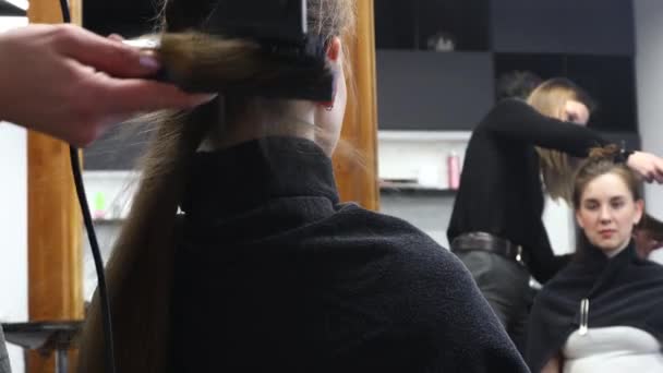 Master parrucchiere donna asciuga i capelli delle ragazze con un asciugacapelli dopo il lavaggio in un salone di bellezza. — Video Stock
