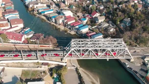 Повітряний вид з дрона на міський приміський поїзд перетинає міст через річку в межах міста. Сочі (Росія) — стокове відео