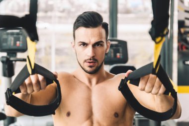 Spor salonunda spor yapan, çıplak vücutlu yakışıklı, genç bir erkek vücut geliştirici.