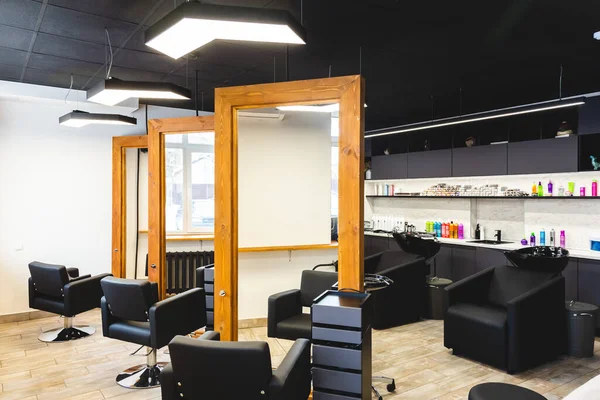 Salone di bellezza barbiere interno. Grandi specchi con cornice in legno e comode poltrone in pelle nera in uno spazio moderno, accogliente e luminoso. — Foto Stock