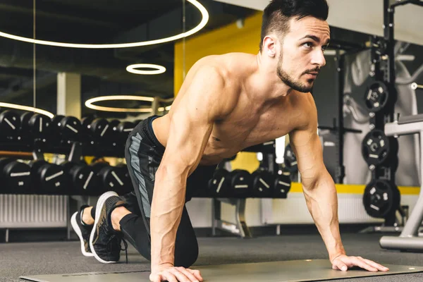 Jóképű fiatal sportos férfi testépítő meztelen felsőtesttel push-up gyakorlatot végez az edzőteremben — Stock Fotó