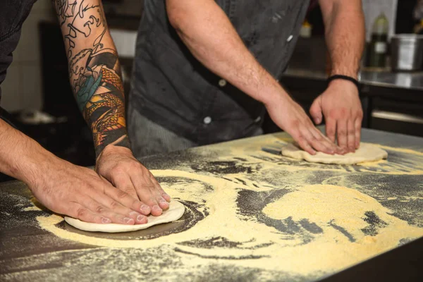 Professional chef cooking in the kitchen restaurant at the hotel, preparing dinner. A cook in an apron makes a pizza. — Stock Photo, Image