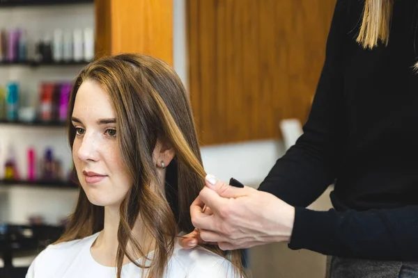 La peluquera maestra riza suavemente a la chica rizadora en un salón de belleza. Peinado del cabello — Foto de Stock