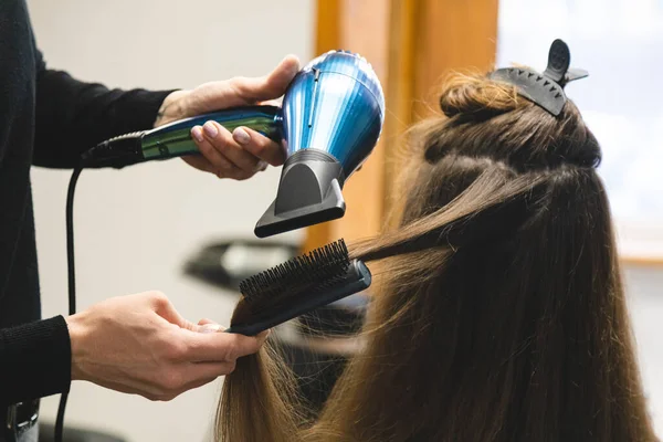 Cabeleireiro mulher mestre seca o cabelo das meninas com um secador de cabelo e pentes após a lavagem no salão de beleza — Fotografia de Stock