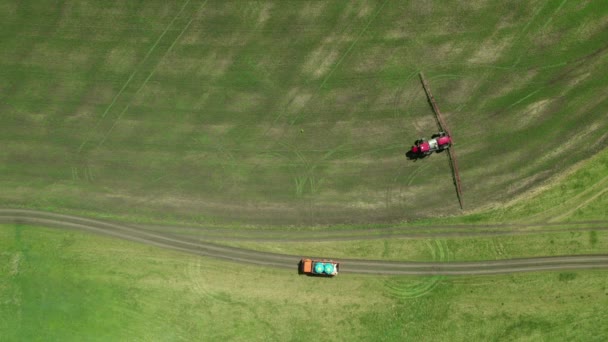 4K Αεροφωτογραφία των αγροτικών μηχανημάτων που καλλιεργούν το χωράφι. Ένα ειδικό τρακτέρ μηχάνημα ψεκάζει τη μελλοντική καλλιέργεια από παράσιτα — Αρχείο Βίντεο