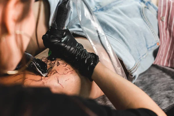 女性のタトゥーアーティストは、体にタトゥーを作る、スタジオで入れ墨をしています。閉鎖だ — ストック写真
