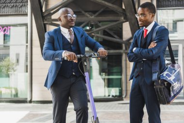 Siyah Afro-Amerikan işadamlarının takım elbiseli ve gözlüklü iki ortağıyla bir şehir bloğunda buluşacağız. Arkadaşlık ve iş ortaklığı