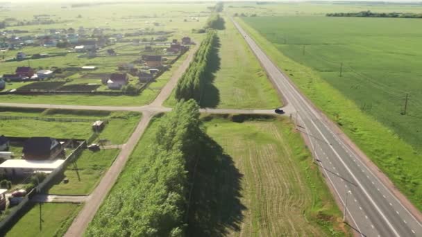 Luftaufnahme der Autobahn mit vorbeifahrenden Autos und Lastwagen an kleinen Dörfern und grünen Feldern und Wiesen. — Stockvideo