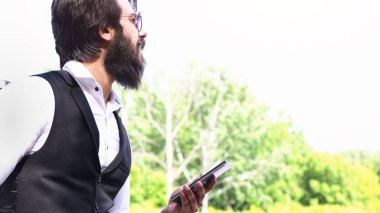 Sakallı, gözlüklü, şık bir takım elbiseli, elinde telefon olan başarılı bir Hindu.