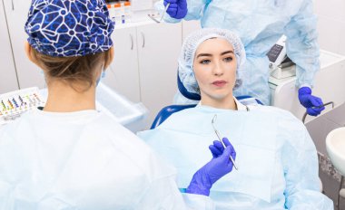 Dişçi konsepti. Profesyonel diş hizmetleri ve acısız modern ekipmanlar. Doktor ve asistanı hastaların dişlerini tedavi ediyor.