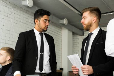 İş yerindeki iki adamın konuşmaları, takım elbiseli genç iş adamlarının ofiste birlikte çalışıp iletişim kurmaları. Şirket buharı ve bir toplantıda yönetici..